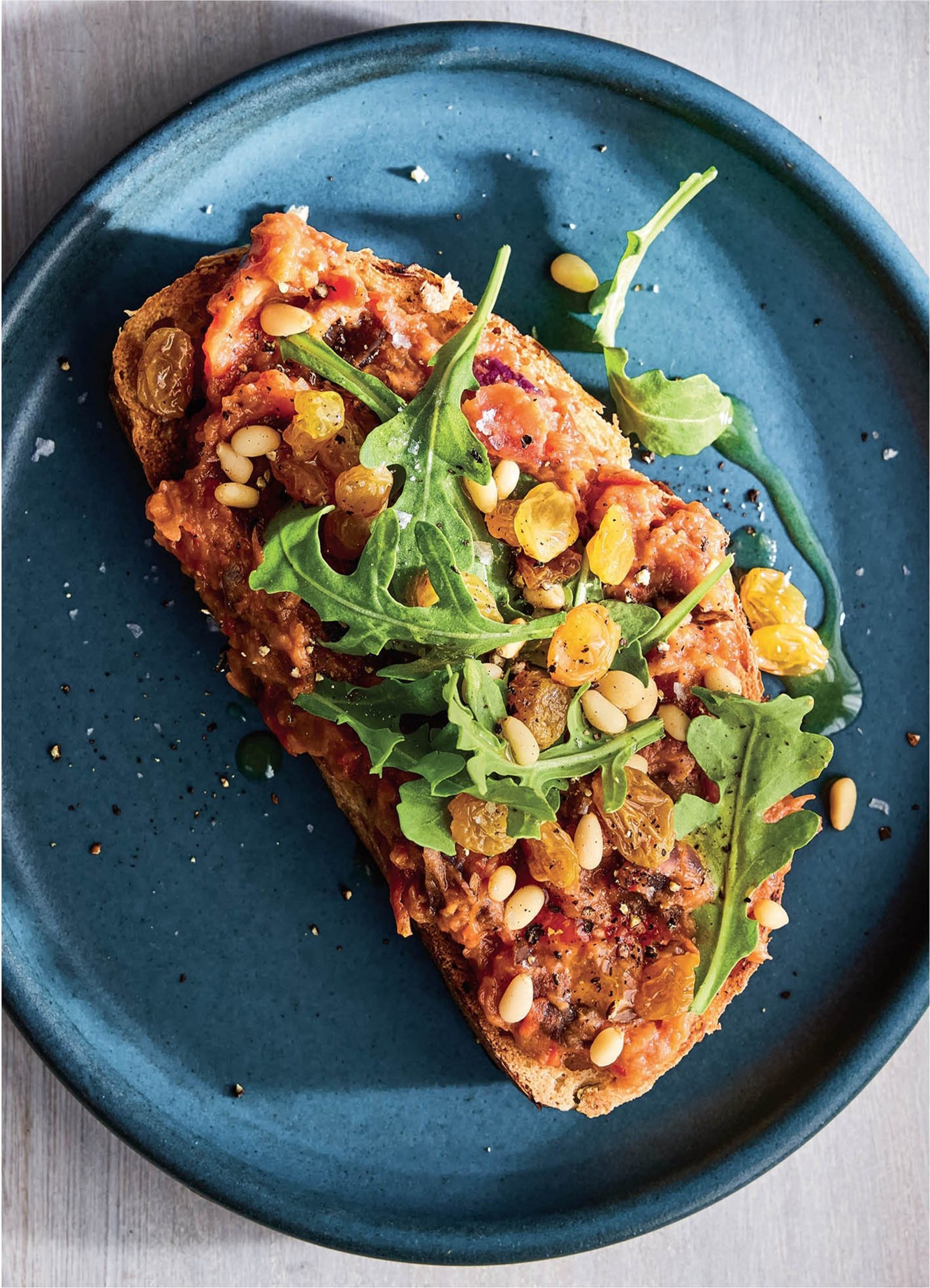 تُوست کاپوناتای بادمجان با روکولا و کشمش ترشی‌شده